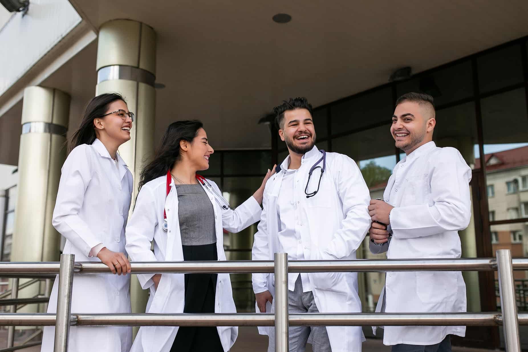 Grupo de quatro médicos alunos de pós-graduação no Brasil juntos sorrindo