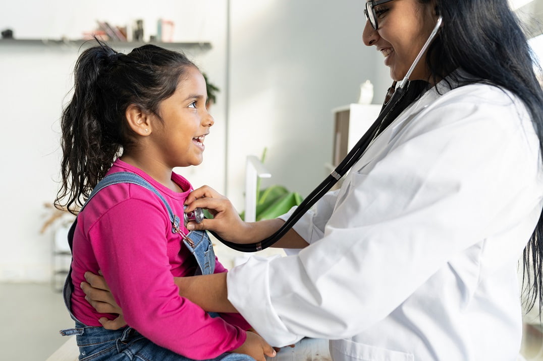 Jovem estudante de curso de formação de médico pediatra atende menina em consultório