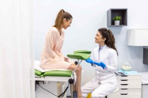 Médica jovem residente na pós-graduação de Ginecologia e Obstetrícia atendendo paciente em consultório